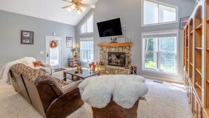 A living room with a fireplace, a sofa, a coffee table, and a TV mounted on the wall. - Solace Mountain Cozy Mountain Retreat with Game Room, sleeps 9, Wifi, private (Franklin)