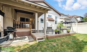 A residential property with a covered patio, outdoor seating, and a barbecue grill.