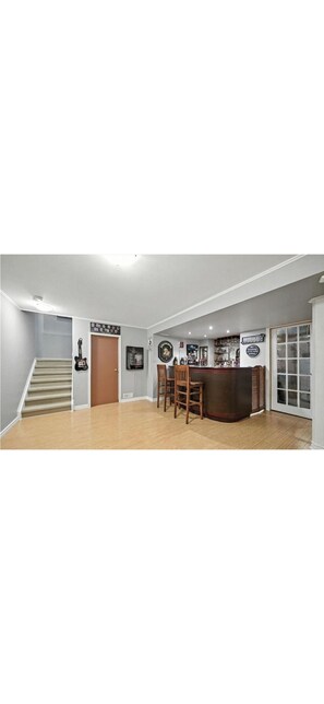 Amplia habitación con escalera, zona de bar con taburetes y puerta que da a otra estancia.