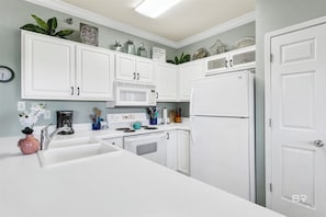 Une cuisine moderne avec des meubles blancs, un évier, une cuisinière et un réfrigérateur.
