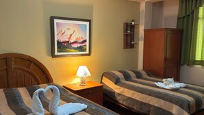 Een hotelkamer met twee bedden, een schilderij aan de muur, een lamp, een kast en een groen gordijn.