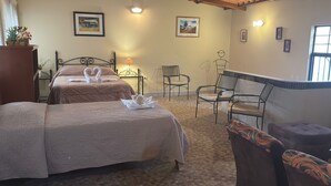 Een hotelkamer met twee bedden, een zithoek met stoelen, een lamp en wanddecoratie.