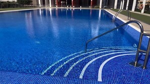 A swimming pool with clear blue water, a tiled edge, and a metal ladder. - Mediterranean Dream Calpe (Calp)