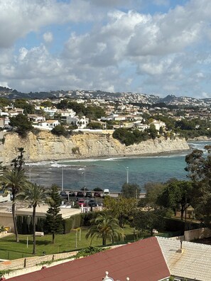 Uma vila costeira com edifícios, um penhasco e uma praia.