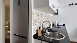 A compact kitchen with a built-in refrigerator, a sink, and a backsplash with patterned tiles. - Mediterranean Dream Calpe (Calp)