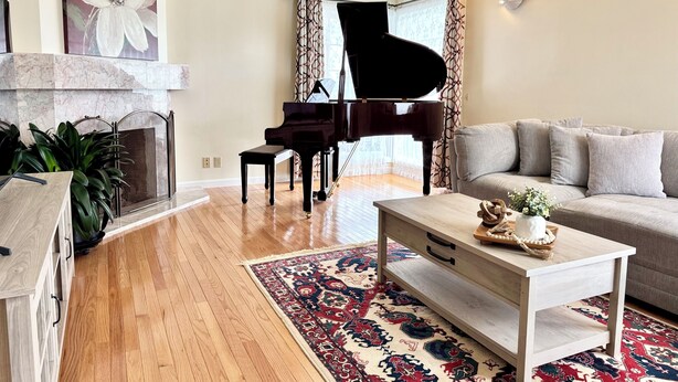 Uma sala de estar com um piano de cauda, um sofá, uma mesa de centro e um tapete estampado.