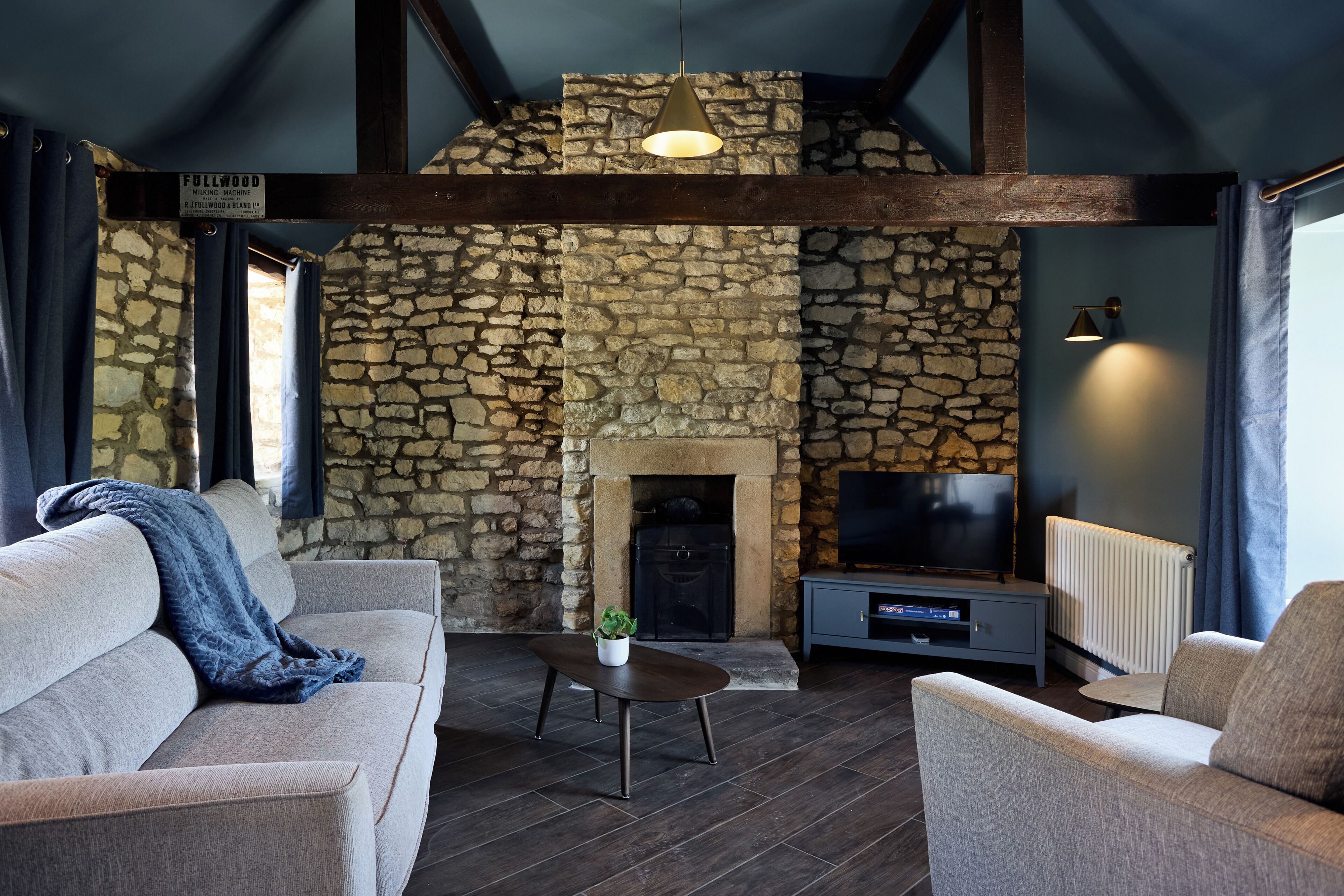 A living room with a stone wall, a fireplace, a sofa, a coffee table, and a television.