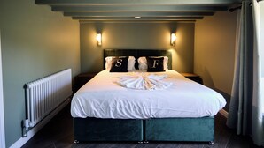 Un dormitorio con cama, dos mesitas de noche, un radiador y una ventana con cortinas.