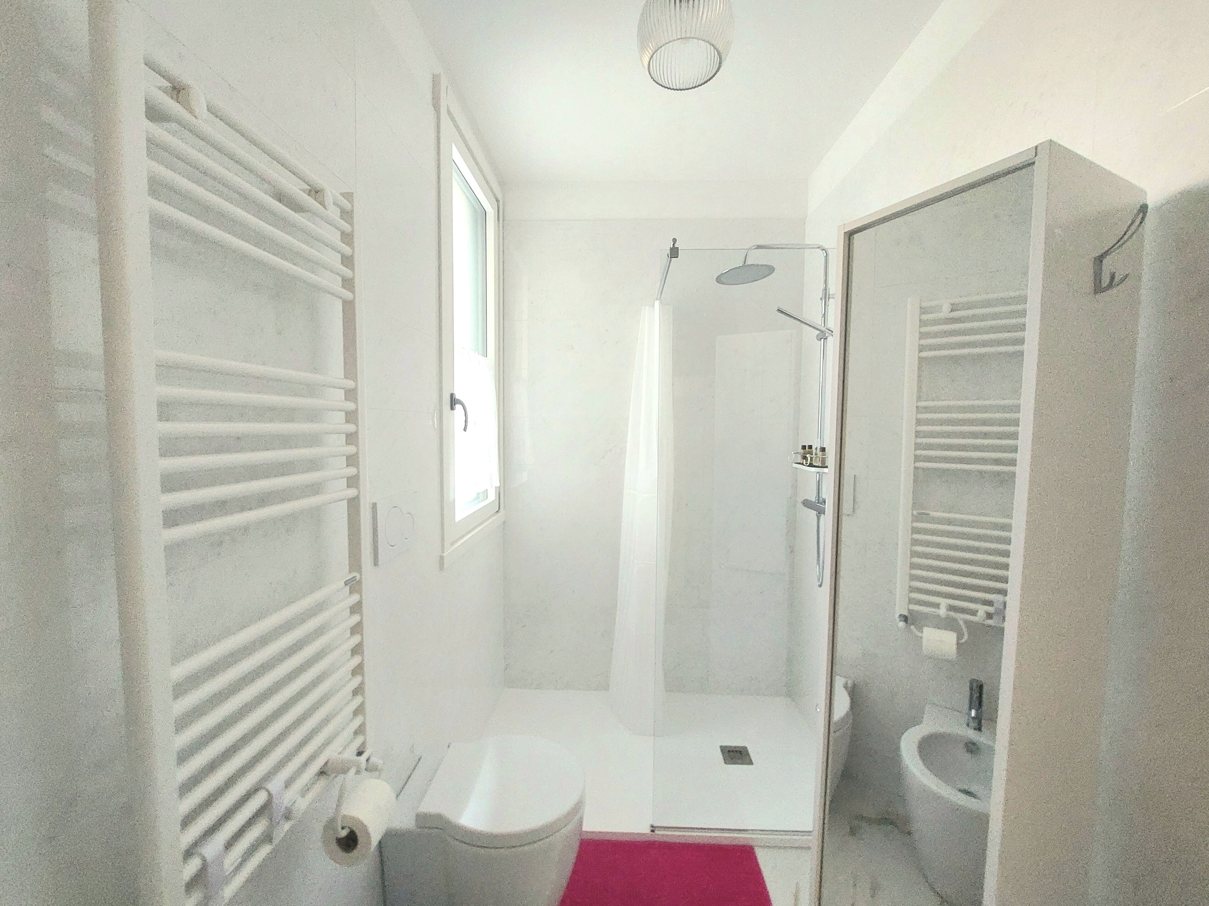 A bathroom with a toilet, a shower, a sink, and a towel rack.
