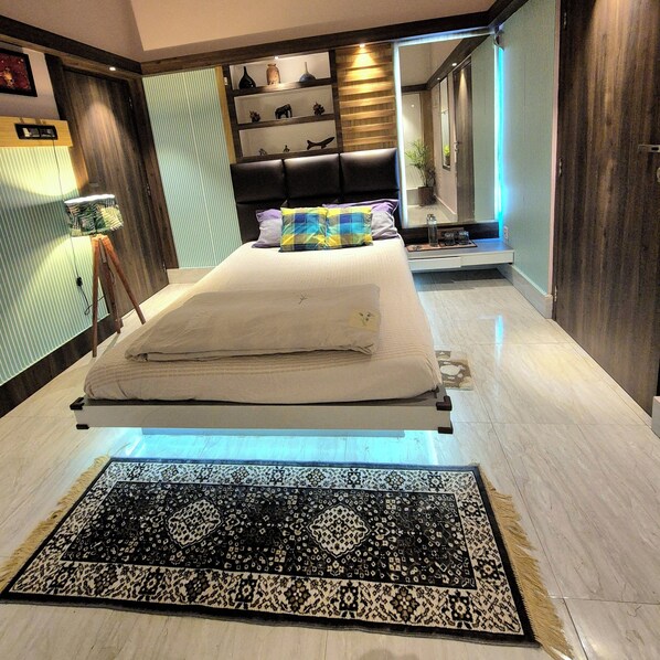 A modern bedroom with a bed, bedside table, lamp, and decorative items.