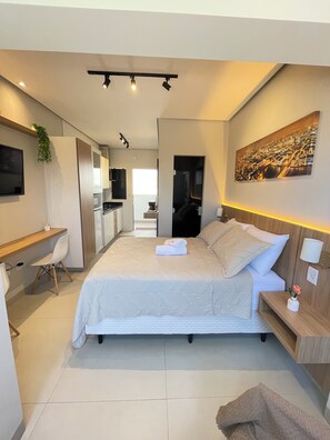 Un dormitorio moderno con cama, mesita de noche y televisor de pared.