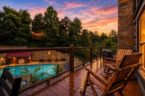 Una terraza de madera con piscina, sillas y un edificio de piedra.