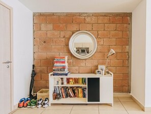 Ein Zimmer mit einer Ziegelwand, einem weißen Bücherregal, einem Spiegel und einer Tür.