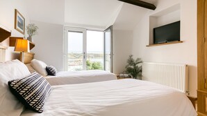 Une chambre d’hôtel avec deux lits, une télévision, une fenêtre donnant sur la mer et un radiateur.