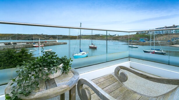 Un balcon avec vue sur un port de plaisance, des bateaux et des immeubles.