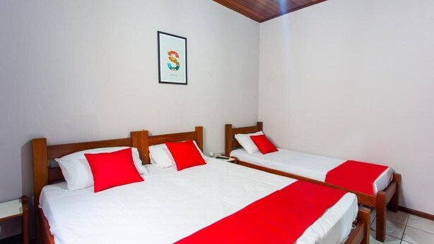 A hotel room with two wooden beds, white bedding, and red pillows. - América Hotel Jacareí (Jacareí)
