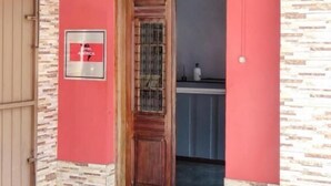 A hotel entrance with a wooden door, a metal gate, and a stone wall. - América Hotel Jacareí (Jacareí)