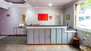 A reception desk with a computer, a small seating area, and a window with a view of the outside. - América Hotel Jacareí (Jacareí)