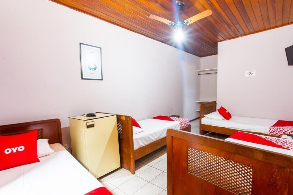 A hotel room with two beds, a wardrobe, a ceiling fan, and a framed picture on the wall.