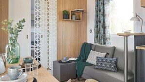 A modern living room with a sofa, a coffee table, a decorative plant, and a window with curtains. - Cozy Caravan in Berlare for 6 People (Berlare)