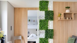 A modern room with a wooden wardrobe, a dining table with plates and glasses, a sofa with a blanket, and a vertical garden wall. - Cozy Caravan in Berlare for 6 People (Berlare)