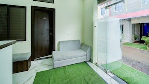 A room with a sofa, a door with a number, a window, and a glass partition. - Deluxe Hotel Sp14 (Indore)