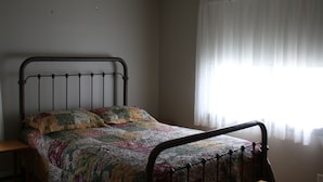 A single bed with a metal frame, a quilt, and a window with sheer curtains. - 3 Bedroom Main Level house located half an hour from Waterton. (Cardston)