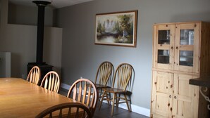 A dining area with a wooden table and chairs, a ceiling fan, a painting on the wall, and a wooden cabinet. - 3 Bedroom Main Level house located half an hour from Waterton. (Cardston)