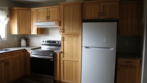 A kitchen with wooden cabinets, a stainless steel oven, and a white refrigerator. - 3 Bedroom Main Level house located half an hour from Waterton. (Cardston)