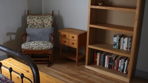 A corner room with a wooden chair, a small wooden table, and a bookshelf filled with books. - 3 Bedroom Main Level house located half an hour from Waterton. (Cardston)