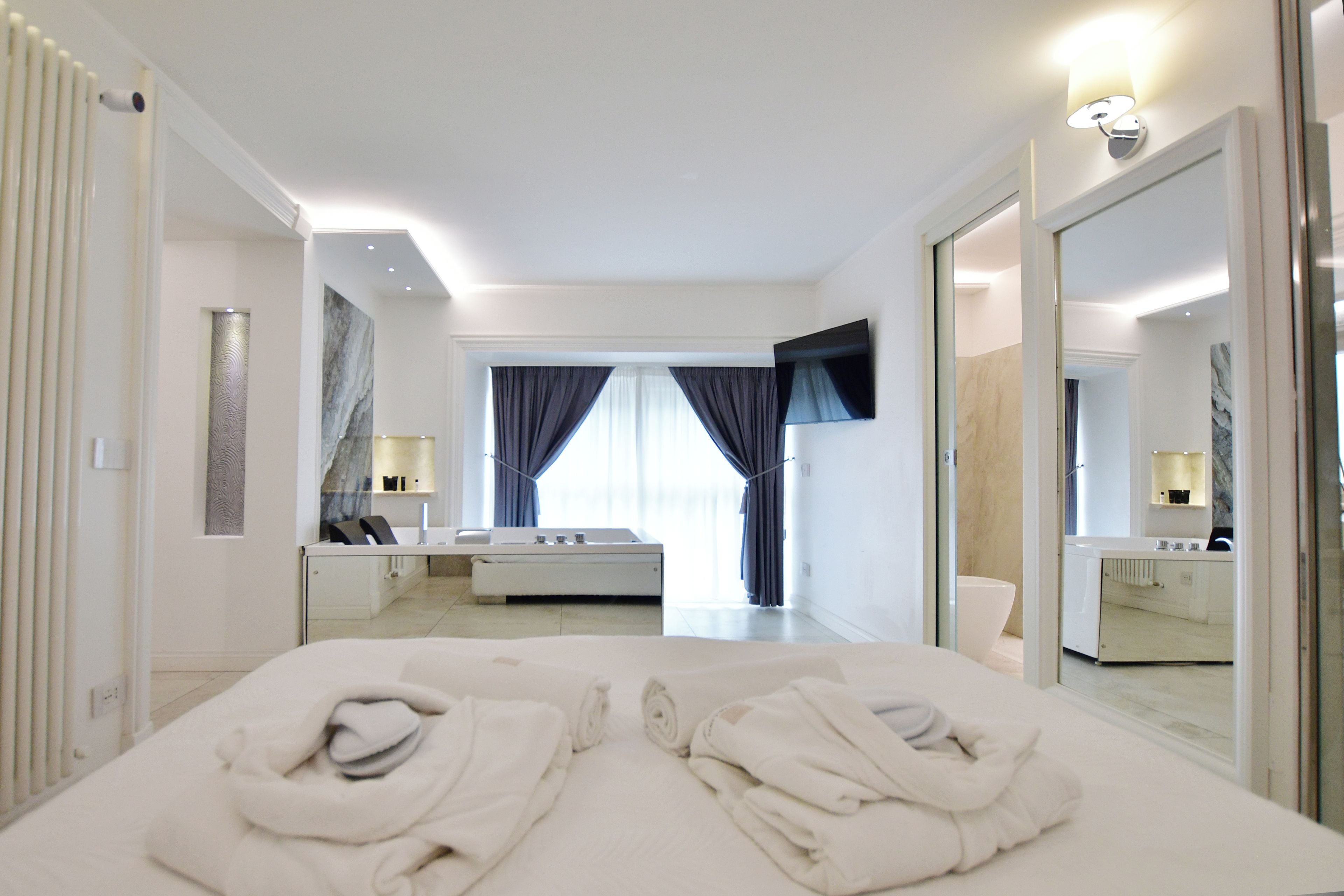 Ein Hotelzimmer mit Bett, Bad, Spiegel und einem Fenster mit Vorhängen.