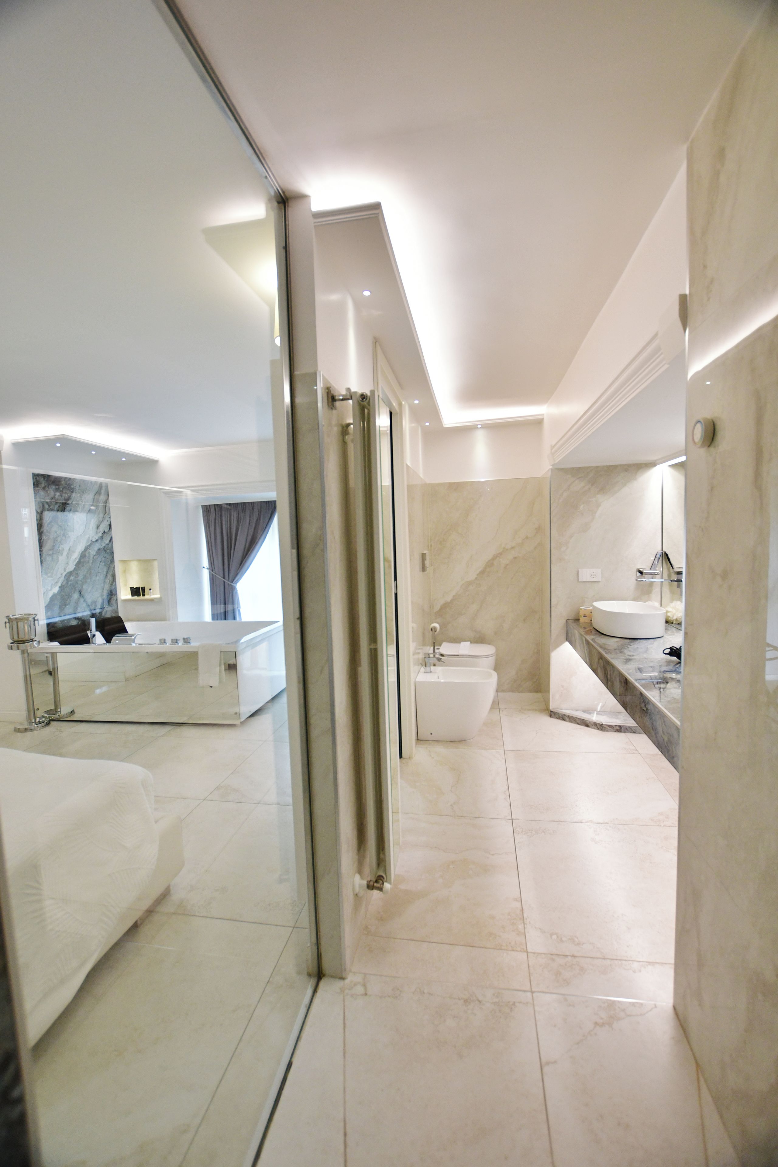 A modern bathroom with a glass shower enclosure, a bidet, and a large mirror.