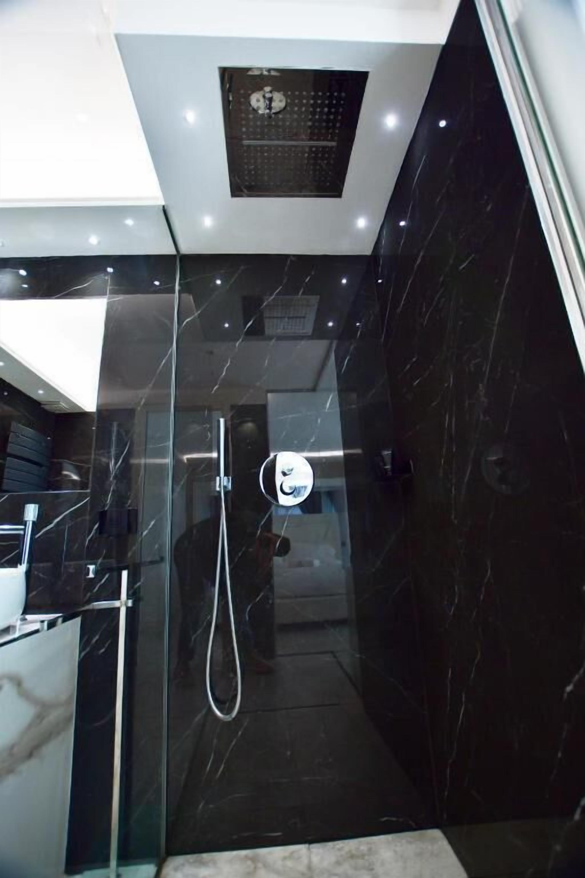 Un bagno moderno con cabina doccia in vetro, vaso a vista e pavimento in marmo.