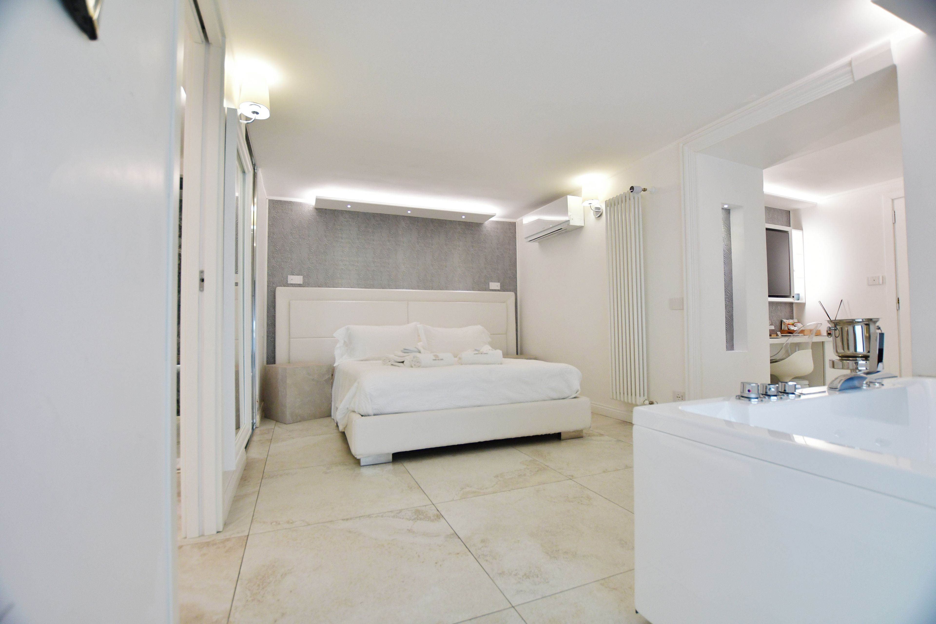 A modern bedroom with a large bed, a separate bathroom with a bathtub, and a walk-in closet.