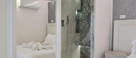 Un dormitorio moderno con un espejo grande, una cama, vestidor y zona de ducha.