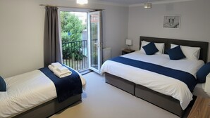 Ein Hotelzimmer mit zwei Betten, einem Balkon, einer Heizung und einem gerahmten Bild an der Wand.