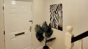 Ein Flur mit einer weißen Tür, einem Blumentopf und einem Wandbild mit Zeprazebra-Muster.