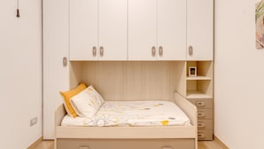 Een slaapkamer met een bed, een kledingkast en een klein plankje.