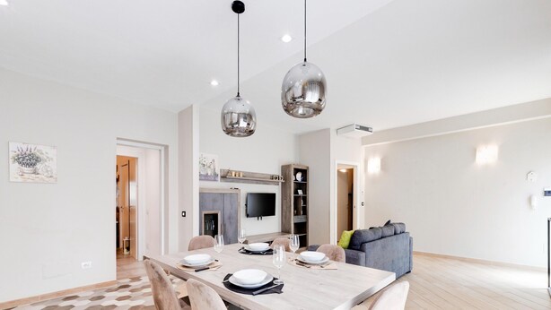 Een moderne eethoek met een houten tafel, stoelen en hanglampen.