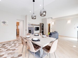 Een moderne eethoek met een houten tafel, stoelen en hanglampen.