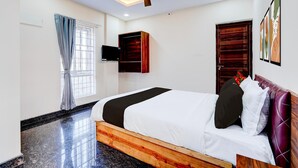 Camera da letto con un letto, ventilatore a soffitto, televisione, armadio in legno e opere d'arte appese al muro.