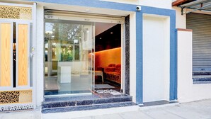 Ingresso di un hotel con una porta in vetro, una porta in legno e una zona con posti a sedere all'interno.