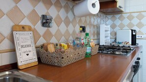 Uma bancada de cozinha com um rolo de papel toalha, uma cesta de pão, uma garrafa de água e uma cafeteira.