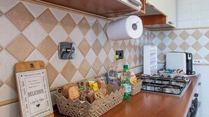 Uma cozinha com bancada de madeira, pia, fogão a gás e painel de azulejos.