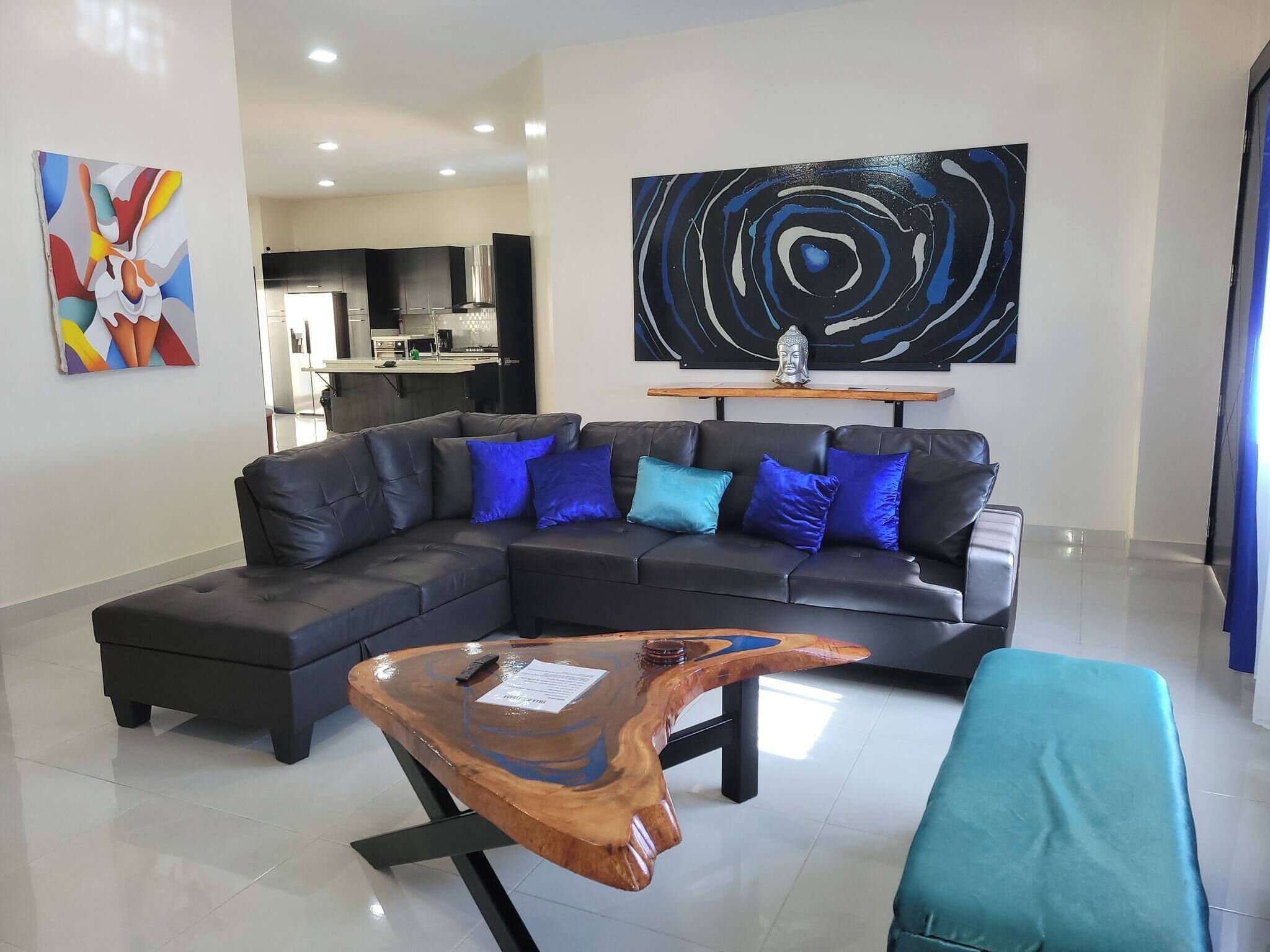 Una sala de estar moderna con un sofá modular, una mesa de centro de madera y un cuadro abstracto grande.