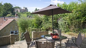 A patio with a table, chairs, and a large umbrella. - 1 Rose Cottage - village of Shipton Gorge, Bridport (Bridport)