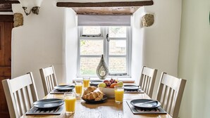 A breakfast table set with plates, glasses, croissants, and fruit. - 1 Rose Cottage - village of Shipton Gorge, Bridport (Bridport)