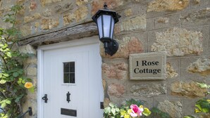 A stone wall with a white door and a sign reading '1 Rose Cottage.' - 1 Rose Cottage - village of Shipton Gorge, Bridport (Bridport)