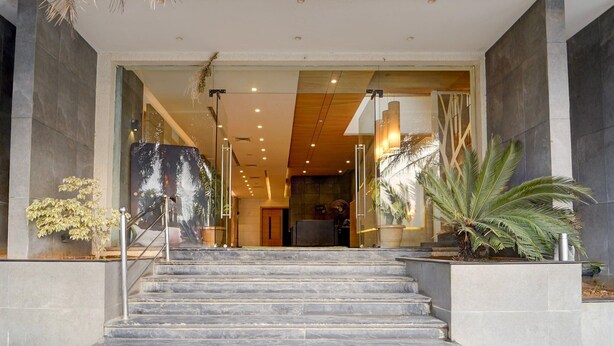 A hotel entrance with marble steps, glass doors, and potted plants. - Deluxe Ramora Grand (Thindukkal)