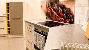 Una cocina moderna con horno empotrado, encimeras de acero inoxidable y una campana extractora grande.